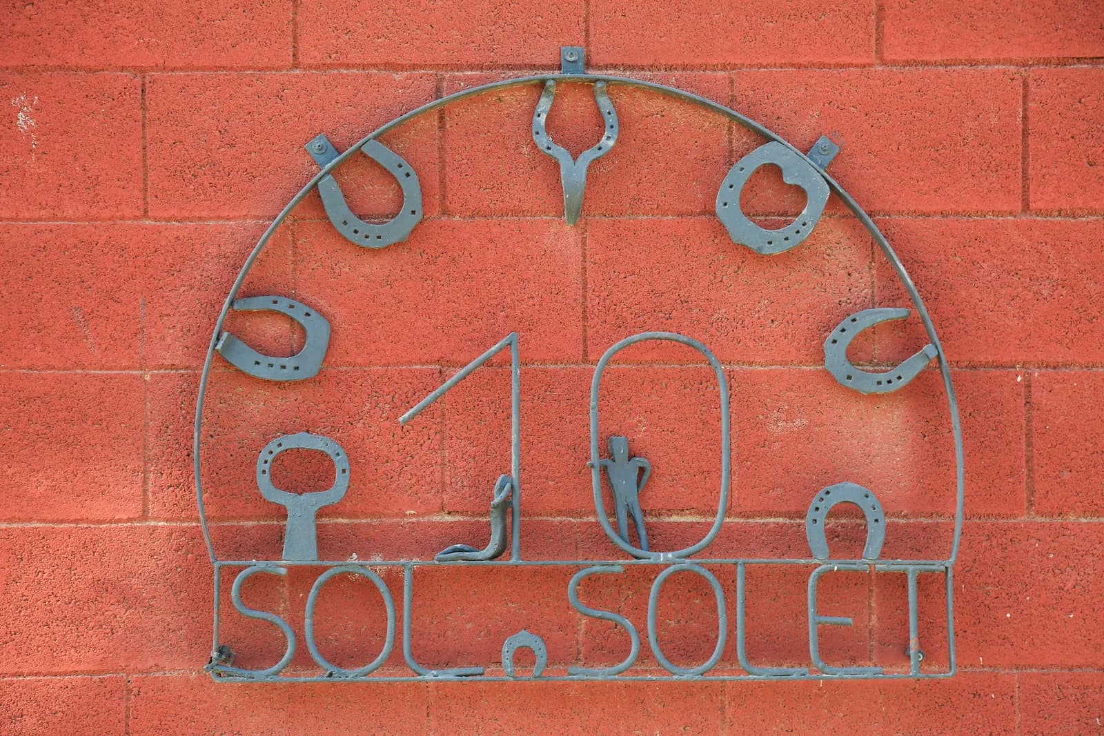 Placa de ferro amb el nom Sol Solet i ferradures a la paret del centre